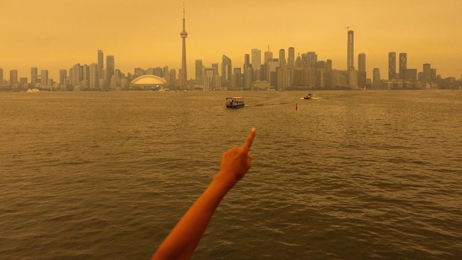 seseorang-menunjuk-ke-cakrawala-saat-menaiki-feri-dari-pulau-toronto-sementara-asap-kebakaran-hutan-dari-ontario-barat-laut-me-1784166617428_169